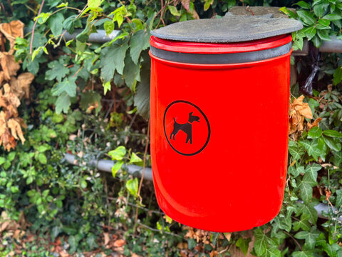 Red Dog Waste Bin Mounted on Fence Line Outdoors