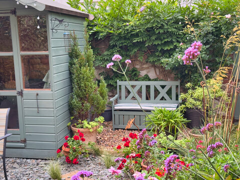 Cozy English Garden Corner with Wooden Shed, Bench, and Blooming Flowers