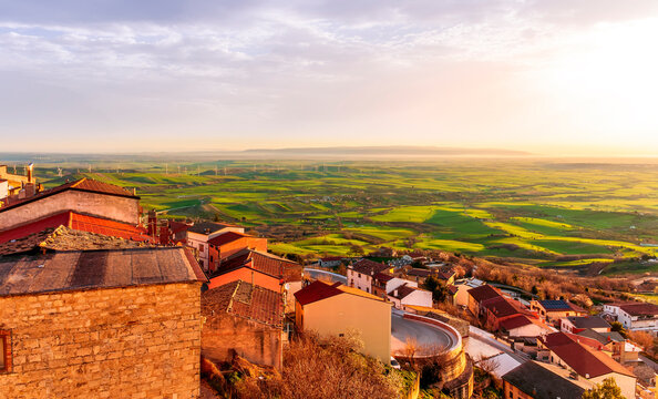 scenic evening sunset landscape with beautiful view og vintage town with traditional roofs and houses and green and golden walley hills with farmland and cloudy sky