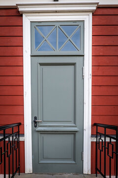 Gray Wooden Door With White Trim on Red House Facade