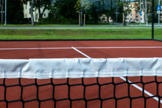 Tennis Net Across an Empty Red Outdoor Court
