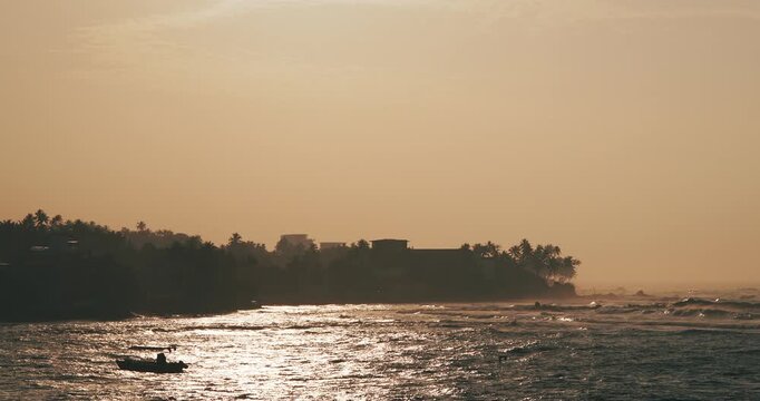 Sri Lanka, Unawatuna. Pearl divers Boat floating on Sea Ocean waves During Sunrise. Seagulls hunting for fishes in ocean. Warm Colors Sea With Waves. Morning haze. Ocean Wave Water Foam Splashes