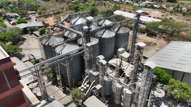 High angle view of a grain processing plant with metallic silos and complex industrial machinery
