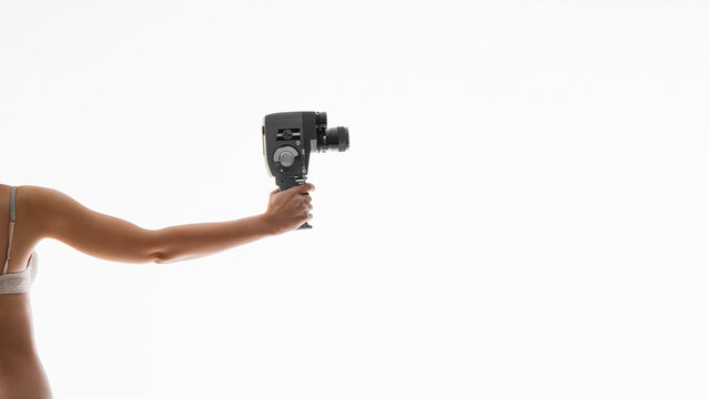 A woman's hand holding retro film camera, isoated on free white background. Vintage cinema poster.