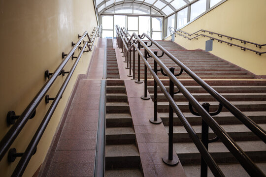 Concrete staircase with accessibility ramp and metal handrails providing barrier free environment at transit station