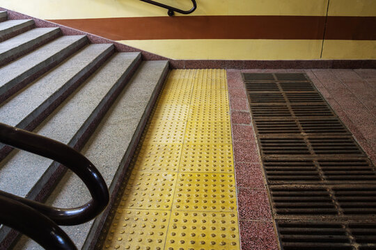 Yellow tactile paving tiles before concrete stairs providing barrier free environment for visually impaired people