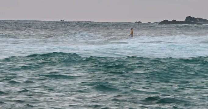 Surfer on the Horizon Amidst Rolling Ocean Waves