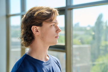 Side view profile portrait of handsome young man looking up near large window © Valerii Honcharuk