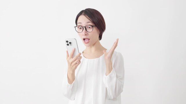 スマートフォンを使うメガネをかけたカットソー姿の女性　ライフスタイルイメージ