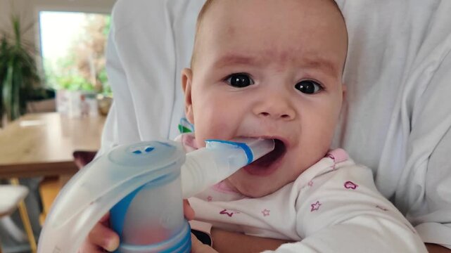 Close up of adorable infant breathing aerosol medicine through inhaler mask. Pediatric respiratory therapy and health care for little child. Cute 6-7 month old baby taking inhalation treatment using n