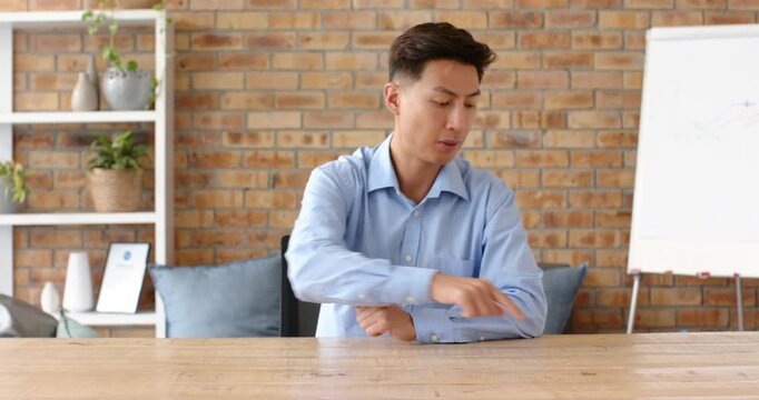 Close up of people talking to the camera, businessman in blue shirt pointing at table while discussi
