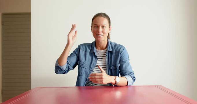 Close up of people talking to the camera, woman in denim jacket sitting at red table