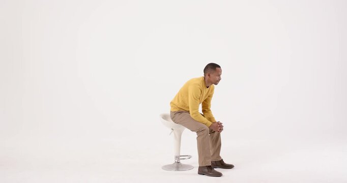 High-speed photography for dynamic scenes, man sitting on stool with arms crossed, wearing yellow sw