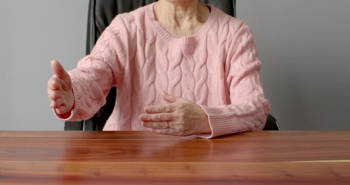 Close up of people talking to the camera, gesturing with hands, woman in pink sweater sitting at tab