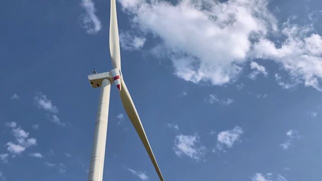 Wind turbine blades spinning against a blue sky generating renewable energy for a sustainable future and demonstrating clean power and environmental technology