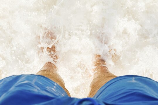 Close-up POV male tourist walking on the unique salt formations and turquoise mineral-rich waters of the Dead Sea beach. A concept for wellness, healthy living, and natural spa travel