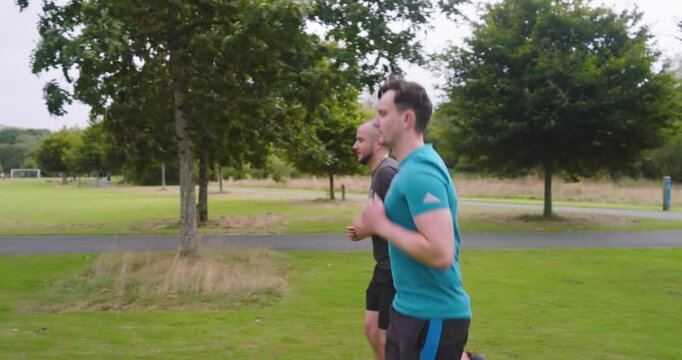 Two men jogging in park, enjoying outdoor exercise and fresh air