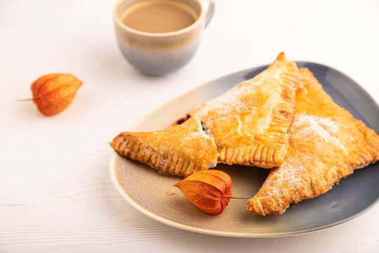 Triangles Pie, Puff Pastry, Samsa with cherry jam on white wooden, side view, close up, selective focus