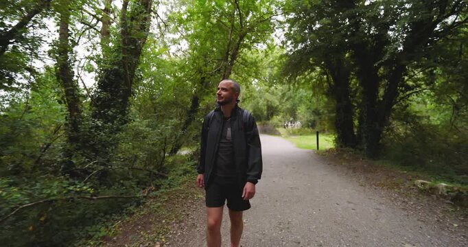 Man walking on forest trail, enjoying nature and fresh air in casual attire