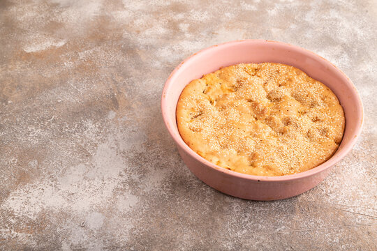 Apple Charlotte cake in baking dish on brown concrete, side view, copy space