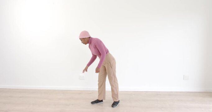 Woman in pink sweater practicing expressive dance moves in minimalist room