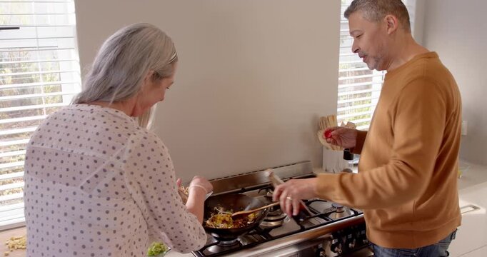 Senior couple cooking together in kitchen, smiling and enjoying preparing meal