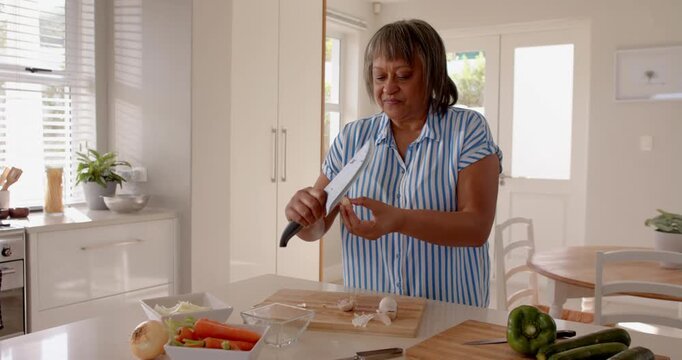 Senior woman chopping vegetables in modern kitchen, preparing healthy meal at home