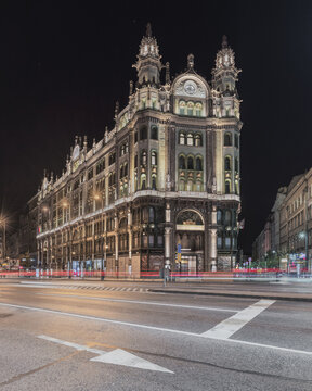 View of the historic Paris Department Store illuminated at night with light trails from passing traffic in Budapest, Hungary.