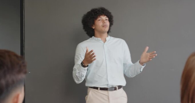 Smiling man giving presentation in office, engaging with audience confidently