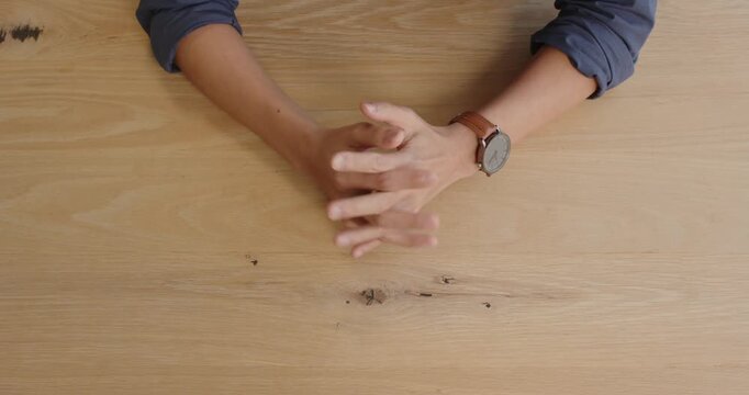 Business professional with watch resting hands on wooden desk, preparing for meeting