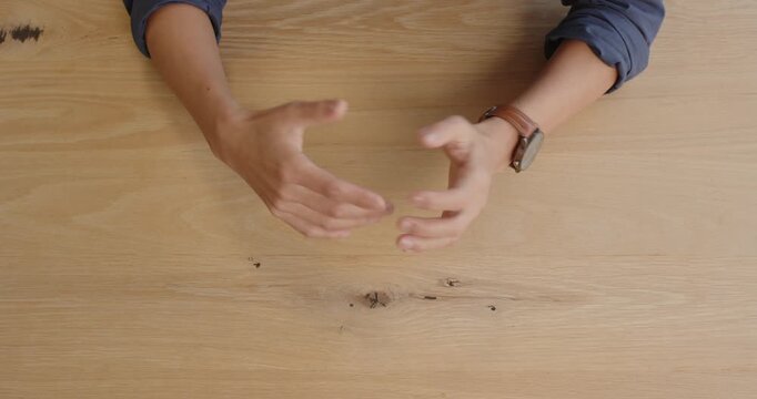 Business professional gesturing with hands on wooden desk during meeting discussion