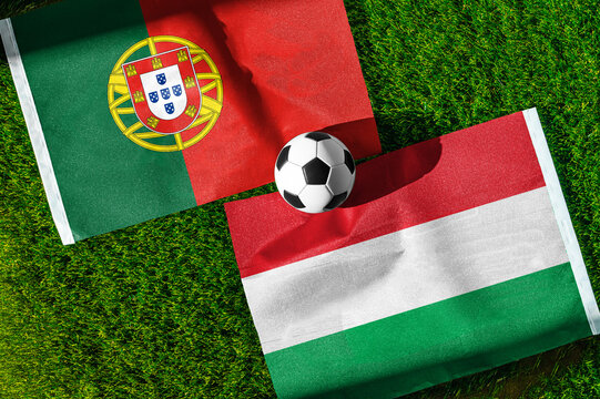 Portugal vs. Hungary football match. National flags on green grass with soccer ball in the middle. Football background for international match.