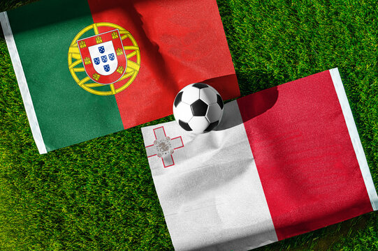 Portugal vs. Malta football match. National flags on green grass with soccer ball in the middle. Football background for international match.