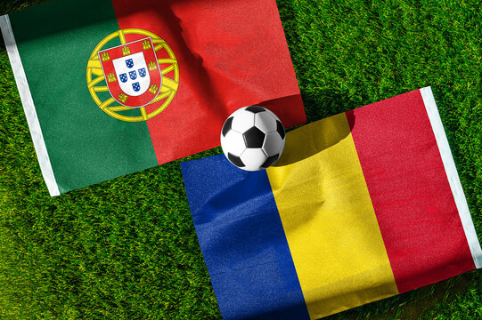 Portugal vs. Romania football match. National flags on green grass with soccer ball in the middle. Football background for international match.