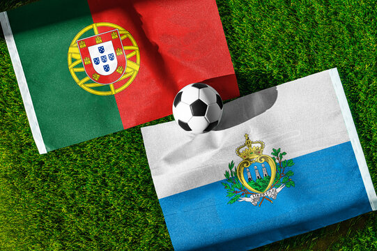 Portugal vs. San Marino football match. National flags on green grass with soccer ball in the middle. Football background for international match.