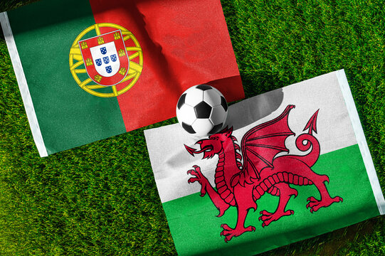 Portugal vs. Wales football match. National flags on green grass with soccer ball in the middle. Football background for international match.