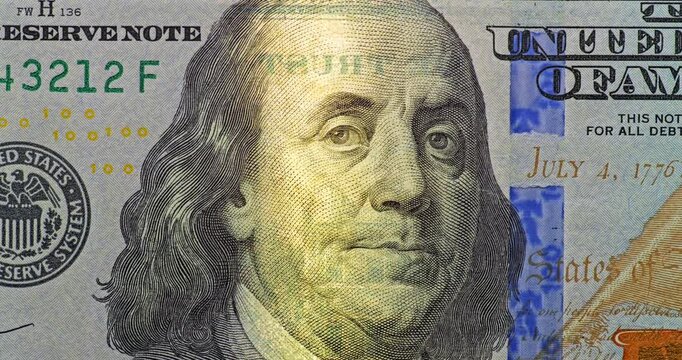 100 dollar bill under moving security scan. 100 dollar bill with Benjamin Franklin portrait moves under security scan and close view highlights crisp engraving blue security strip.