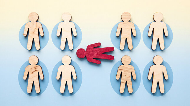 Red wooden figure lying down among standing figures concept of failure or exclusion in group setting