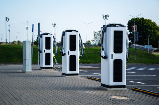 Brand new electric car charging stations wrapped in protective plastic film standing on empty paved parking lot in city