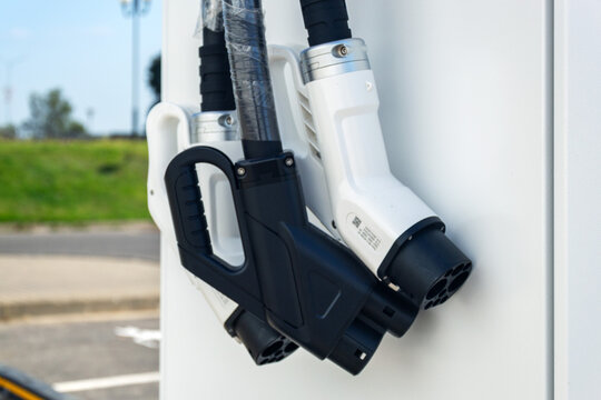 Close up of new electric car charging plugs wrapped in protective plastic film on brand new terminal