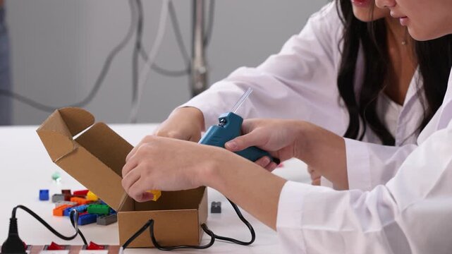 Teenage Students Using Hot Glue Gun for Science Project in Classroom