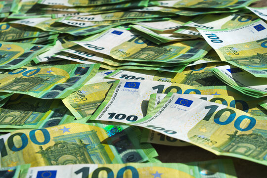 Macro close-up of many 100 euro notes focusing on fine details, security elements and texture, illustrating wealth and cash money concept.