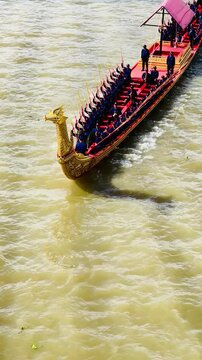 High angle view of rowers paddling a traditional golden royal barge during a rehearsal processional ceremony along the Chao Phraya River in Bangkok, Thailand.