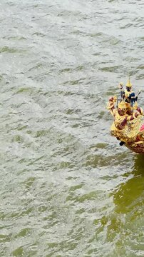 High angle view of rowers paddling a traditional golden royal barge during a rehearsal processional ceremony along the Chao Phraya River in Bangkok, Thailand.