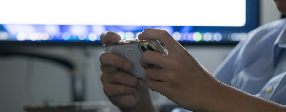 自宅で勉強に集中せずスマホを触る学生、学習中にスマートフォンに触れる学生、ドーパミン中毒注意　手元のクローズアップ顔無しのイメージのバナー