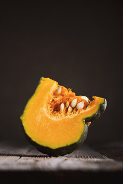 Fresh cut pumpkin slice arranged in warm dramatic lighting on wooden surface. Rustic autumn composition with squash and seasonal cooking mood