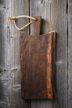 Small knife with wooden handle lying on an old cutting board on rusty aged table