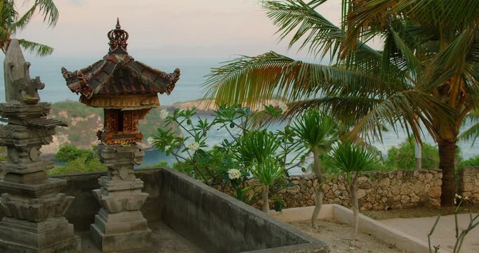 Traditional Balinese shrine overlooks the turquoise ocean and rocky islands at sunset