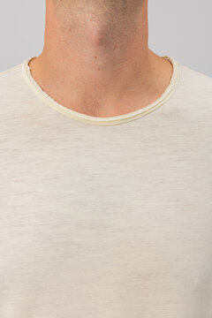 Close-up detail of a man's neck wearing a cream crew neck t-shirt with a raw distressed collar edge. Showcases soft heather knit texture. Ideal for menswear apparel design and mockups.