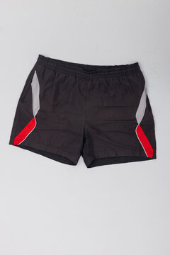 Men's black athletic sports shorts with red and grey side accents flat lay on white studio background. Ideal product shot for activewear apparel, gym clothing, and e-commerce mockup template.